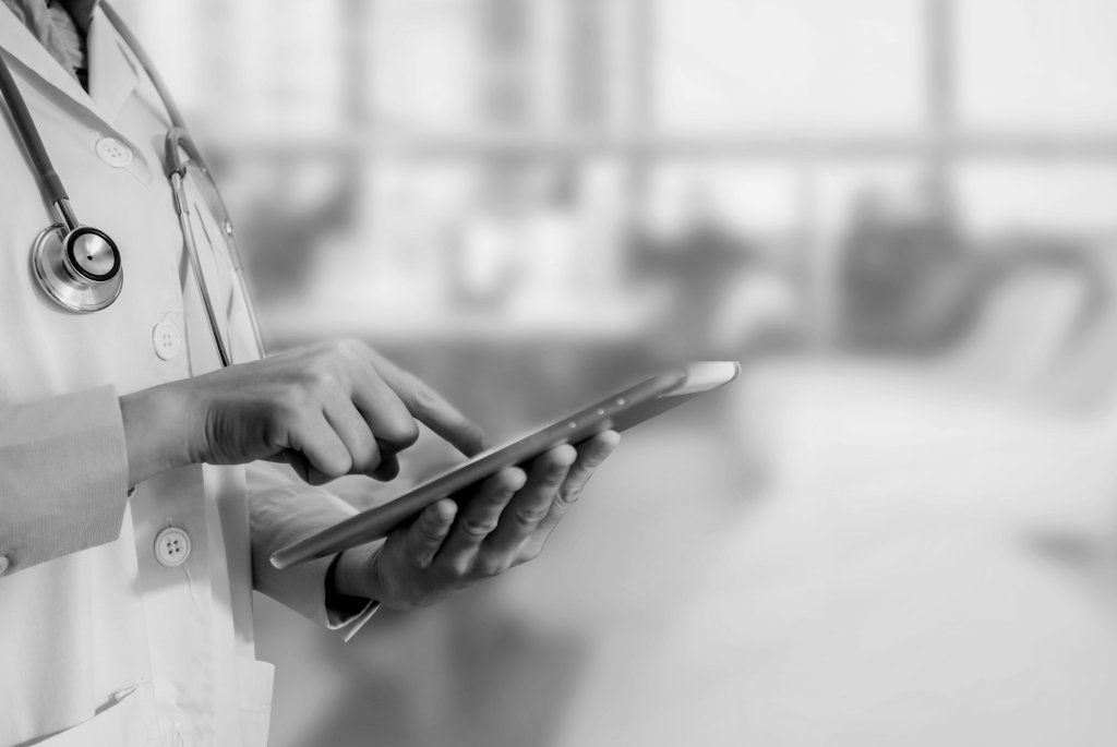 Svartvitt foto på läkare som använder en surfplatta 