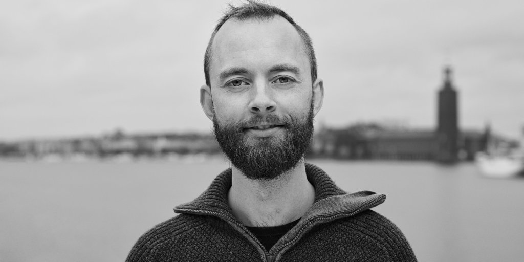 Svartvit porträtt bild utomhus på Bouvets medarbetare Jonas Pettersson. Stockholms Stadshus syns i bakgrunden.