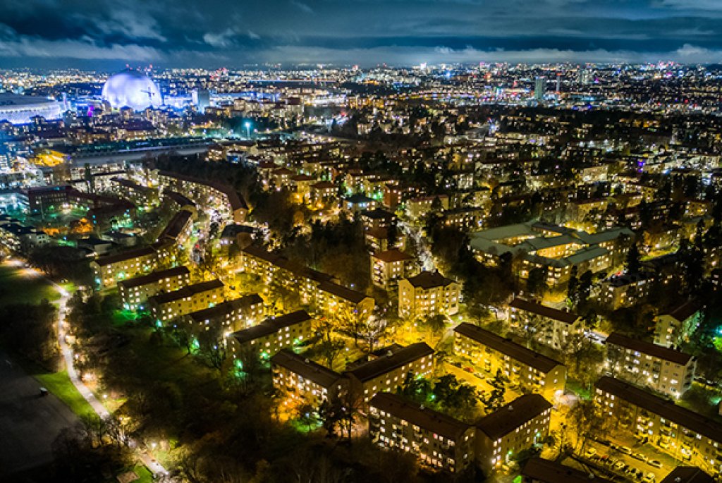Flygfoto som visar hur en stor del av Stockholm, inklusive Globen, är el-upplyst i mörkret. Symboliserar hur viktig strömmen är i och för staden. 